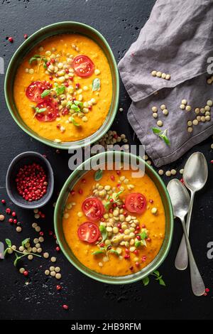 Hausgemachte Linsensuppe mit Kirschtomaten und Rahm. Gelbe Linsensuppe aus Gemüse. Stockfoto