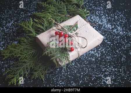 Vintage Geschenkbox mit Tannenzacken und roten Beeren auf einer Kreidetafel. Geschenkbox mit Schnee auf dunklem Hintergrund. Stockfoto