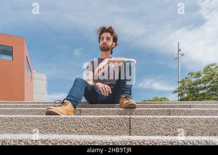 Bärtiger Kerl, der auf Stufen sitzt Stockfoto