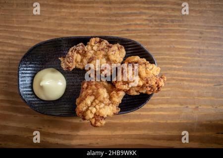 Im japanischen Restaurant werden Karaage oder japanisches gebratenes Huhn mit Mayo auf einem Holztisch serviert. Stockfoto