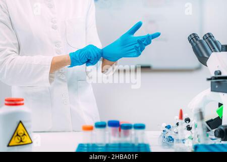 Laborant legt Schutzhandschuhe an. Stockfoto
