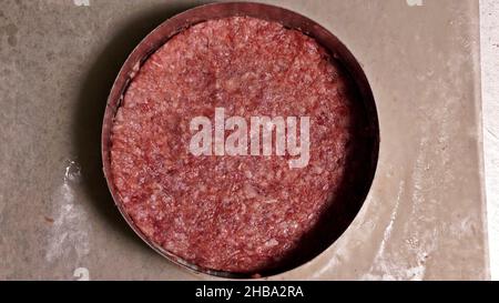 Kochen macht Fleisch Medaillons für Burger. Koch in schwarz Handschuhe macht Schnitzel essen. Die koteletts sind in Stahl Ring in eine noch Medaillon eingeebnet. Stockfoto