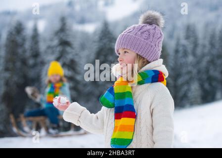 Kleine Mädchen und Jungen genießen einen Tag im Winterwald spielen. Kinder Geschwister haben Spaß im schönen Winterpark. Frohe Kindheit. Stockfoto