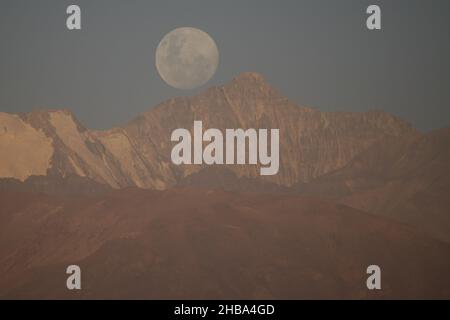 Santiago, Metropolitana, Chile. 17th Dez 2021. Der fast Vollmond im Dezember, genannt der kalte Mond, erscheint hinter dem Altarhügel, in den Anden, aus Santiago, Chile. Kredit: ZUMA Press, Inc./Alamy Live Nachrichten Stockfoto