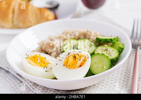 Frühstück Haferbrei mit gekochtem Ei, Gurke und Sesam. Gesunde, ausgewogene Ernährung. Stockfoto