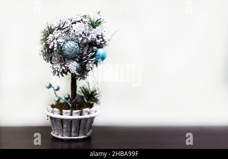 Kleiner weihnachtsbaum in einem Topf mit blauen Kugeln auf weißem Hintergrund Stockfoto