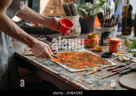 Maler, der in seinem Arbeitsbereich moderne abstrakte Kunst mit farbenfrohen Gouachen auf Leinwand schuf Stockfoto