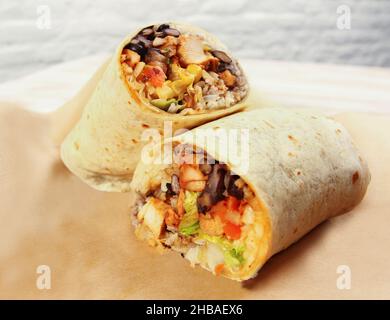 Mexikanischer Burrito in zwei Hälften serviert mit Huhn und Gemüse Interieur Stockfoto