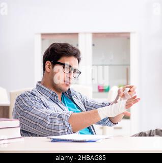 Der junge Student Mann mit der Hand Verletzungen der Vorbereitung für die Prüfungen Stockfoto