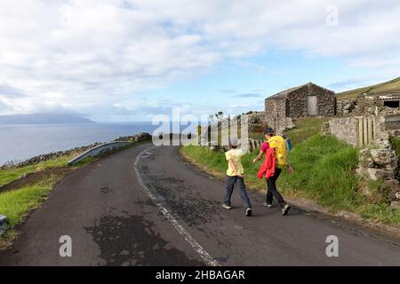 Mutter und Sohn wandern bergab auf der Straße vom Caldeirao Krater, Corvo Insel, Azoren, Portugal Stockfoto