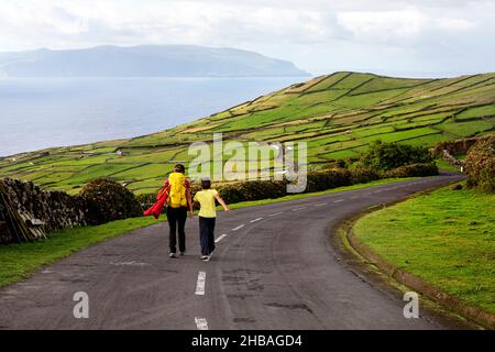 Mutter und Sohn wandern bergab auf der Straße vom Caldeirao Krater, Corvo Insel, Azoren, Portugal Stockfoto