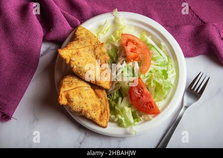 Samosa auf einem Teller mit Salat und Tomaten. Horizontale Ansicht von oben. Stockfoto