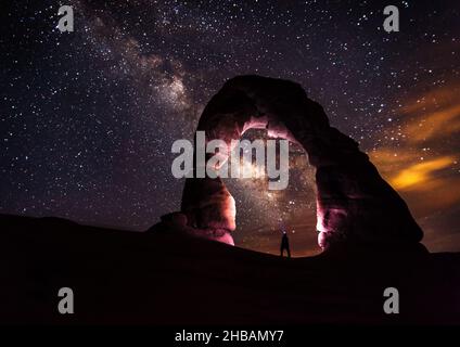 Delicate Arch in der Nacht von einsamer Person mit Stirnlampe beleuchtet; die Milchstraße im Himmel darüber. Arches National Park, Utah, Vereinigte Staaten von Amerika. Eine einzigartige, optimierte Version eines Bildes von NPS Ranger JW Frank; Quelle: NPS/Jacob W. Frank Stockfoto