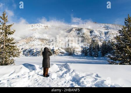 Besucher fotografieren den Roaring Mountain im dichten Schnee. Yellowstone-Nationalpark, Wyoming, Vereinigte Staaten von Amerika. Eine einzigartige, optimierte Version eines Bildes von NPS Ranger JW Frank; Quelle: NPS/Jacob W. Frank Stockfoto