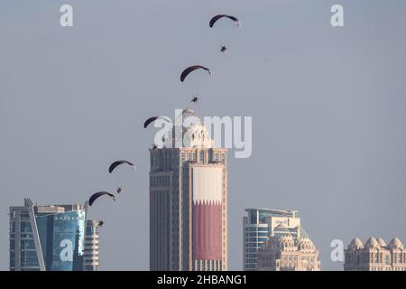 Doha, Katar. 18th Dez 2021. Fallschirmjäger steigen in einer Formation ab, während sie während einer Militärparade zum Qatar National Day mit Hilfe von Paramotoren fliegen. Quelle: Mahmoud Hefnawy/dpa/Alamy Live News Stockfoto