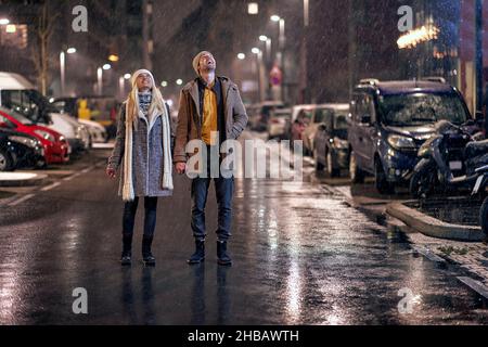 Glückliches junges Paar, das in der Nacht in einer wunderschönen Stadt herumläuft Stockfoto