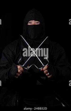 Asian man trägt Ninja Kostüm und hält Ninja Waffen Stockfoto