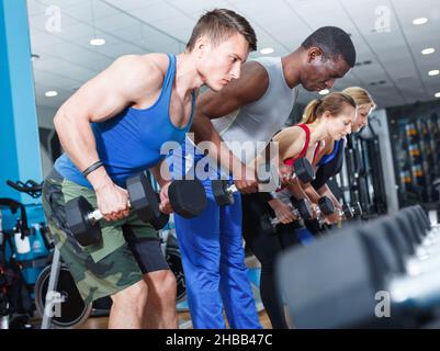 Portrait von sportlichen jungen Menschen, die im Fitnessstudio mit Hanteln Übungen machen Stockfoto