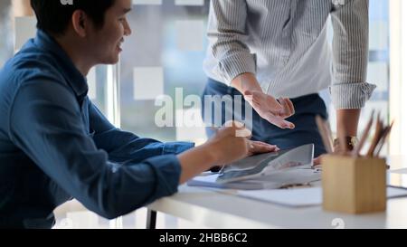 Zwei junge Männer, die im Büro über ein Projekt diskutieren, sind gut gelaunt. Stockfoto