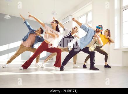 Gruppe von fröhlich lächelnden jungen zeitgenössischen Tänzern in trendigen Gläsern, die im Studio tanzen Stockfoto