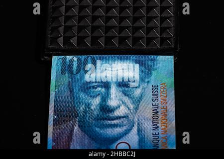 Nahaufnahme von 100 schweizer Franken-Banknoten auf einer schwarzen Brieftasche isoliert auf dunklem Hintergrund Stockfoto