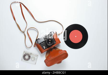 Retro-Stil Nostalgie Hintergrund. Retro-Kamera in Ledertasche mit Riemen, Vinyl-Schallplatte, Audiokassette auf weißem Hintergrund. Draufsicht Stockfoto