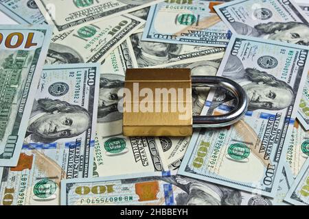 Goldenes Schloss mit Schlüssel auf dem Hintergrund der Dollarscheine Stockfoto