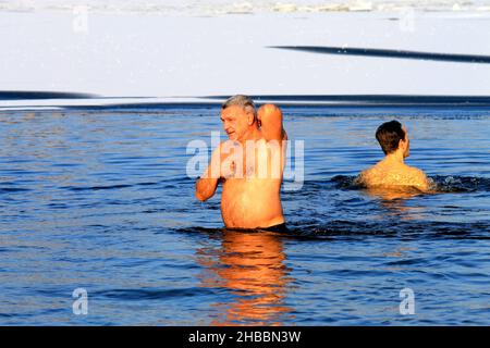 Winterschwimmen, härtend. Während des orthodoxen Feiertages von Epiphanie schwimmen Männer in einem mit Eis bedeckten Fluss. Wintersport, Dnipro, Ukraine, Dnepr, 2020 Stockfoto