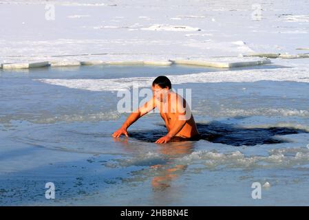 Winterschwimmen, härtend. Während des orthodoxen Feiertages von Epiphanie schwimmen Männer in einem mit Eis bedeckten Fluss. Wintersport, Dnipro, Ukraine, Dnepr, 2020 Stockfoto