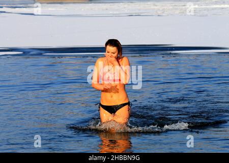 Winterschwimmen, verhärtet, Frau schwimmen in einem mit Eis bedeckten Fluss während des orthodoxen Feiertages von Epiphanie. Wintersport, Dnipro, Ukraine, Dnepr, 2020 Stockfoto