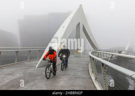 Glasgow, Großbritannien. 18th Dez 2021. Am frühen Morgen wurden Pendler von einem frostigen Nebel verwöhnt, der eine surreale Landschaft über dem Fluss Clyde und seinen Brücken, insbesondere der Tradeston Bridge (auch bekannt als die Squinty Bridge) und der Portland Suspension Bridge, schuf. Kredit: Findlay/Alamy Live Nachrichten Stockfoto