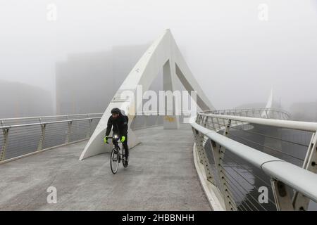 Glasgow, Großbritannien. 18th Dez 2021. Am frühen Morgen wurden Pendler von einem frostigen Nebel verwöhnt, der eine surreale Landschaft über dem Fluss Clyde und seinen Brücken, insbesondere der Tradeston Bridge (auch bekannt als die Squinty Bridge) und der Portland Suspension Bridge, schuf. Kredit: Findlay/Alamy Live Nachrichten Stockfoto