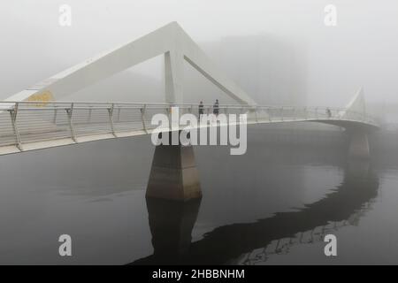 Glasgow, Großbritannien. 18th Dez 2021. Am frühen Morgen wurden Pendler von einem frostigen Nebel verwöhnt, der eine surreale Landschaft über dem Fluss Clyde und seinen Brücken, insbesondere der Tradeston Bridge (auch lokal bekannt als die Squiggly Bridge) und der Portland Suspension Bridge, schuf. Kredit: Findlay/Alamy Live Nachrichten