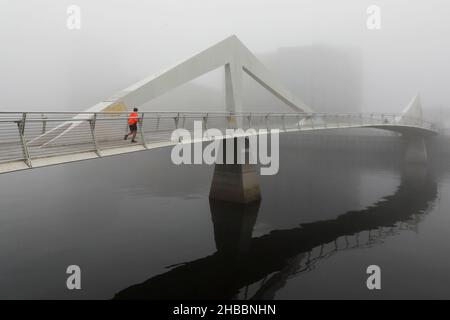 Glasgow, Großbritannien. 18th Dez 2021. Am frühen Morgen wurden Pendler von einem frostigen Nebel verwöhnt, der eine surreale Landschaft über dem Fluss Clyde und seinen Brücken, insbesondere der Tradeston Bridge (auch bekannt als die Squinty Bridge) und der Portland Suspension Bridge, schuf. Kredit: Findlay/Alamy Live Nachrichten Stockfoto