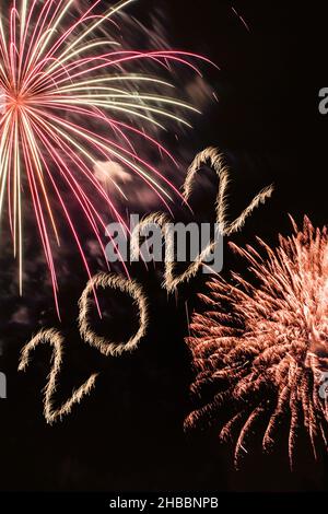 Frohes Neues Jahr 2022. Funkelnde brennende Zahlen Jahr 2022 mit Feuerwerk auf schwarzem Hintergrund. Stockfoto
