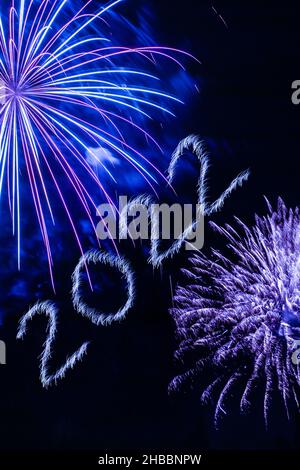 Frohes Neues Jahr 2022. Funkelnde brennende Zahlen Jahr 2022 mit Feuerwerk auf schwarzem Hintergrund. Stockfoto