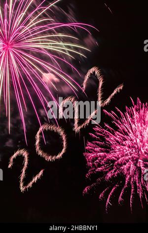 Frohes Neues Jahr 2022. Funkelnde brennende Zahlen Jahr 2022 mit Feuerwerk auf schwarzem Hintergrund. Stockfoto