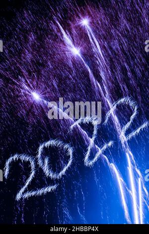 Frohes Neues Jahr 2022. Funkelnde brennende Zahlen Jahr 2022 mit Feuerwerk auf schwarzem Hintergrund. Stockfoto