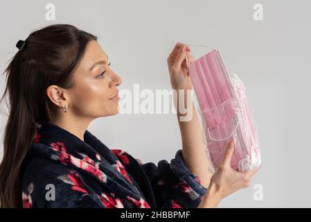 Salisbury, Wiltshire, Großbritannien. 2021. Frau, die während des Covids eine rosafarbene medizinische Maske aus der Packung nimmt. Stockfoto