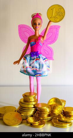 Barbie-Puppe mit einer Schokolade verpackt mit geprägter 1-Euro-Münze goldene Folie, Stapel von Euro-Münzen Pralinen, Stockfoto