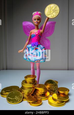 Barbie-Puppe mit einer Schokolade verpackt mit geprägter 1-Euro-Münze goldene Folie, Stapel von Euro-Münzen Pralinen, Stockfoto