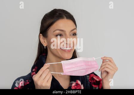 Salisbury, Wiltshire, Großbritannien. 2021. Frau, die während des Covids eine rosafarbene medizinische Maske auf ihr Gesicht legt. Stockfoto