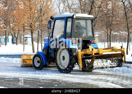 Winterreinigung der Straßen der Stadt. Der Traktor entfernt im Winter frischen Schnee von einer verschneiten Straße. Dnipro City, Dnepr, Ukraine Stockfoto