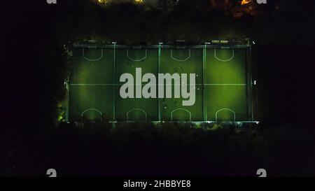 Fußballspieler, die auf dem Fußballfeld herumlaufen. Workout am Abend. Vorbereitung auf das Spiel. Luftaufnahme mit einer Drohne aus einer Höhe. Fußballe oder SoC Stockfoto