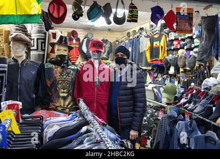 Ein Ladenbesitzer oder Ladenbesitzer in seinem Bekleidungsgeschäft, der während der COVID 19-Pandemie eine Maske trägt, Broadway Market, Tooting Bec, London, Großbritannien Stockfoto