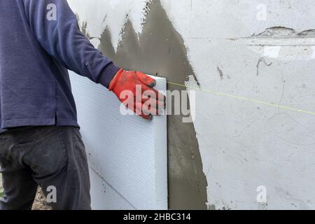 Bauarbeiter installieren Styropor-Dämmplatten an der Hausfassadenwand für den thermischen Schutz. Stockfoto