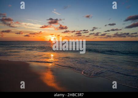 Strand umgeben vom Meer mit Segelbooten auf ihm während des Sonnenuntergangs in Aruba, Karibik Niederlande Stockfoto