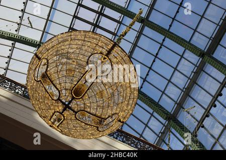 Glockenförmige goldene Weihnachtsdekorationen mit schönen kleinen warmen Lichtern im zentralen Bereich der Glaskuppel der Mall of the Emirates, Dubai, VAE. Stockfoto