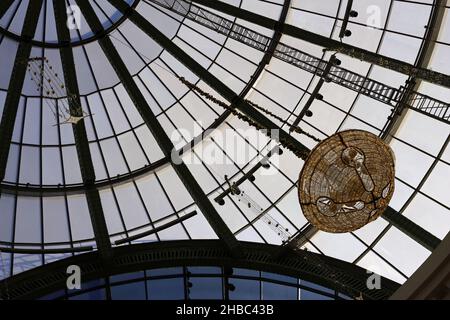 Glockenförmige goldene Weihnachtsdekorationen mit schönen kleinen warmen Lichtern im zentralen Bereich der Glaskuppel der Mall of the Emirates, Dubai, VAE. Stockfoto