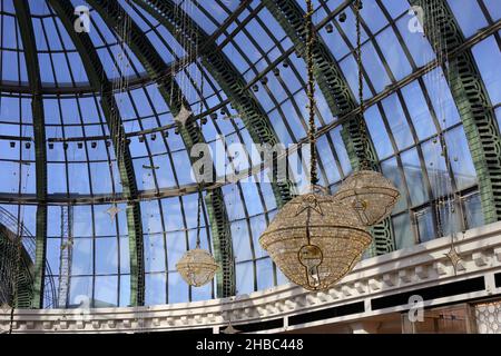 Glockenförmige goldene Weihnachtsdekorationen mit schönen kleinen warmen Lichtern im zentralen Bereich der Glaskuppel der Mall of the Emirates, Dubai, VAE. Stockfoto